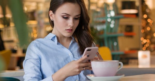 woman using phone with coffee