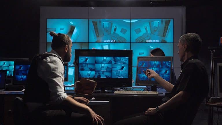 Surveillance team in a modern office with large live screens