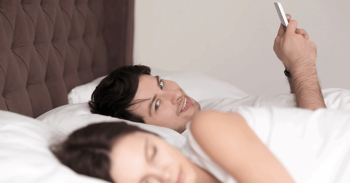 man emotionally cheating with his phone while in bed